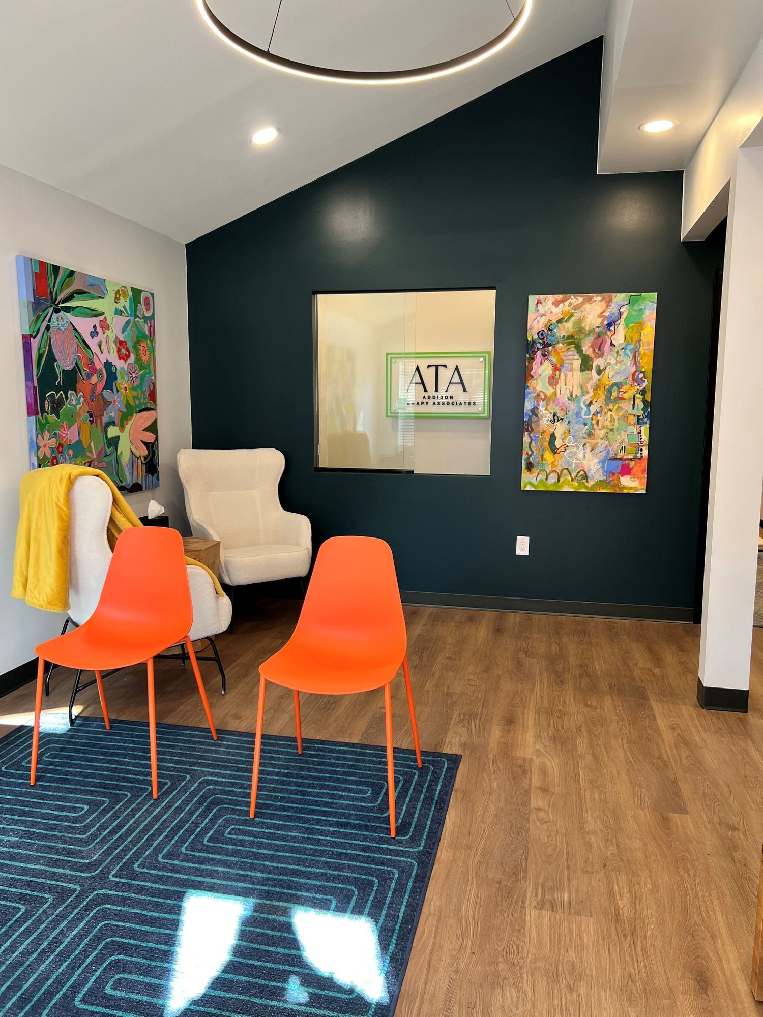 Bright Addison Therapy Associates therapy office with an arched window, green chairs, and framed art prints on the wall