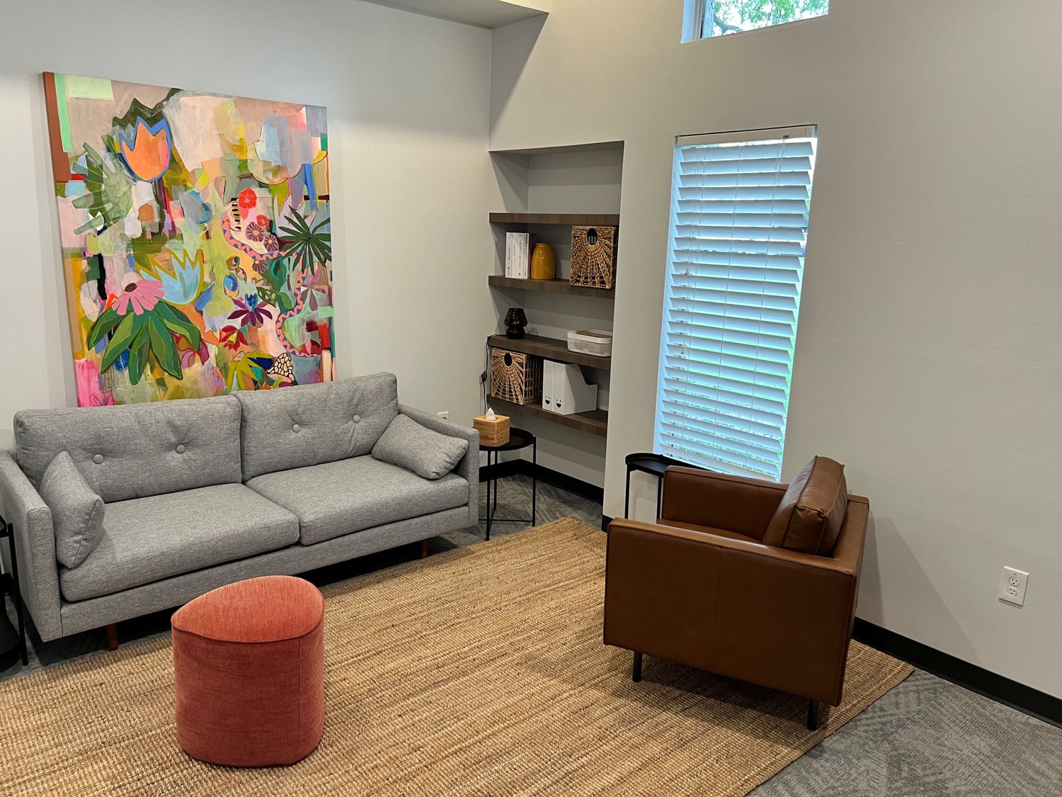 Warm therapy office interior at Addison Therapy Associates featuring tan leather seating, walnut shelving, and natural light
